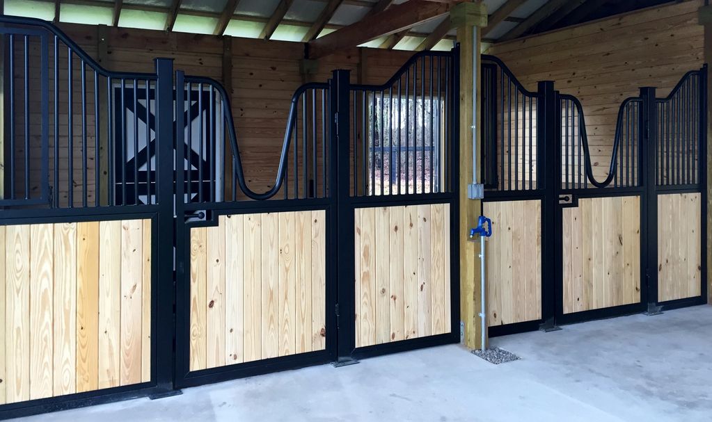 Modern horse stable with black metal and wood stalls.