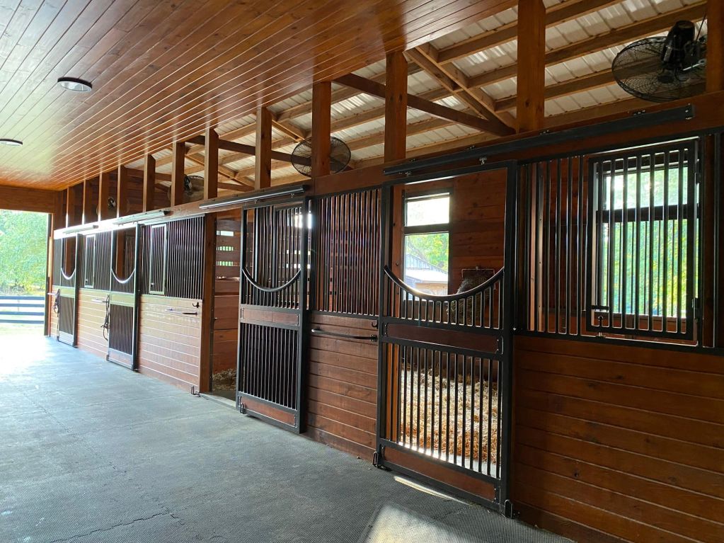 Interior of a well-maintained wooden horse stable with metal gates.
