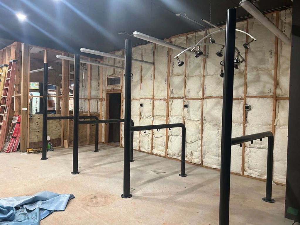 Interior under construction with black metal poles and exposed insulation walls.