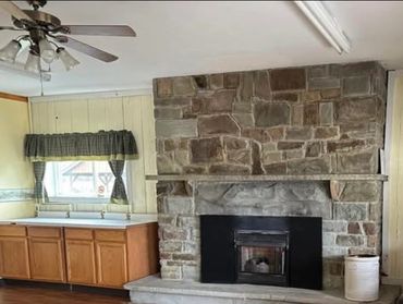 Cozy living room with stone fireplace and wooden floor.