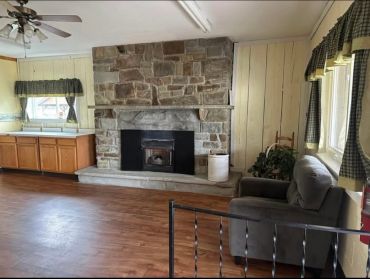 Cozy living room with stone fireplace and wooden floor.