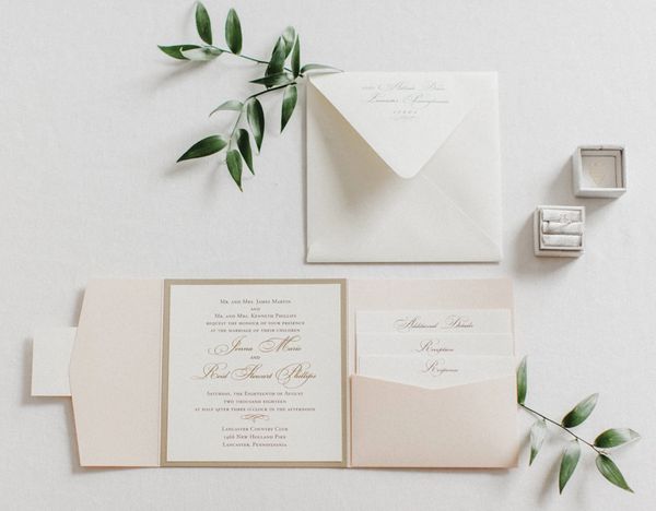 Elegant wedding invitation suite with greenery accents and ring boxes.