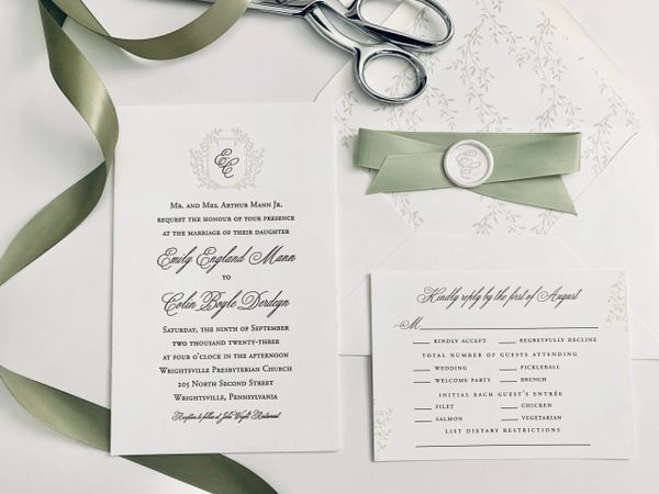 Elegant wedding invitation set with green ribbon and wax seal.