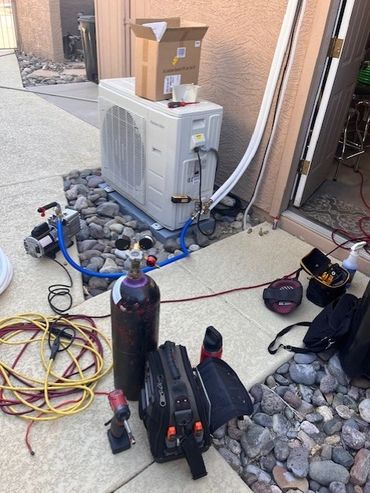 Tools and equipment set up for air conditioning or refrigeration work outside a building.