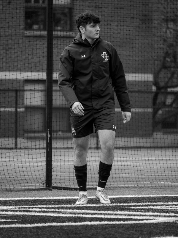 Young male athlete in sportswear standing on a soccer field.