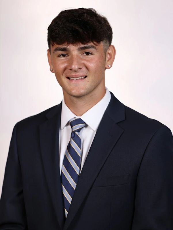 Young man in a suit and striped tie smiling at the camera.