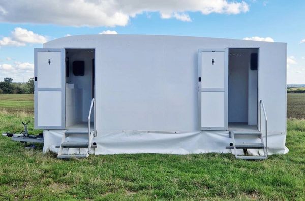 Portable outdoor restroom trailer with open doors.