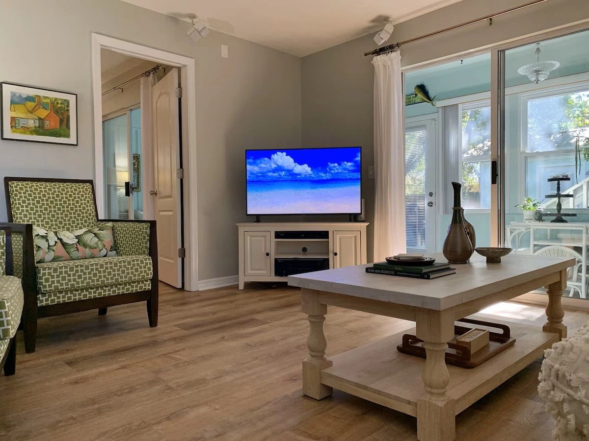 Cozy living room with green-patterned chairs and a bright TV screen.