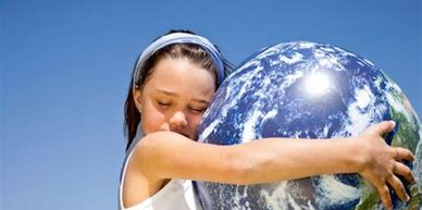 a girl holds a beach ball sized globe of the earth and with eyes closed is hugging it with love