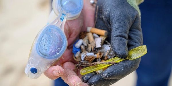 Hands holding  marine litter with plastic and cigarette butts on a beach