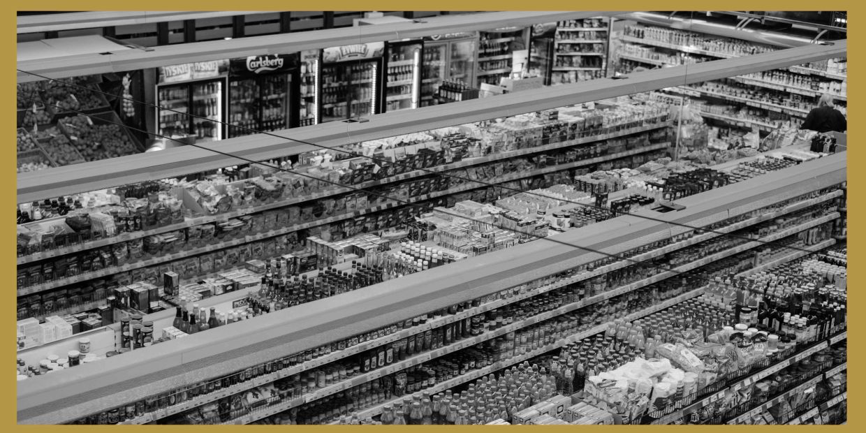 Aerial view of supermarket aisles with stocked shelves and a person shopping.