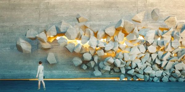 man standing in front of a wall that is crumbling and light coming through