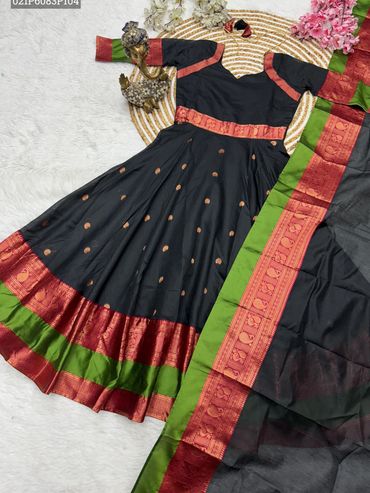 Black traditional dress with red and green borders laid out with a brass Ganesha statue.