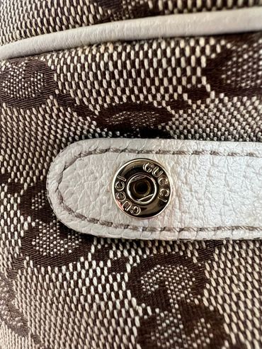 Close-up of a Gucci button on textured fabric strap.