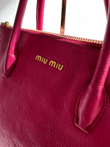 Close-up of a pink Miu Miu leather handbag with gold accents.