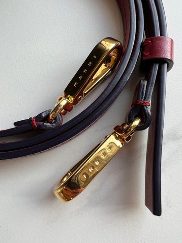 Close-up of a leather strap with gold clasps engraved with 'MARNI'.