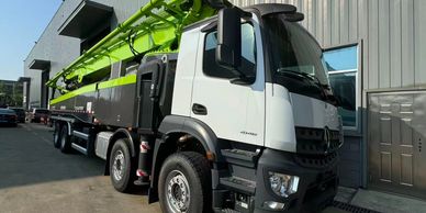 A large white and green construction truck parked beside a building.