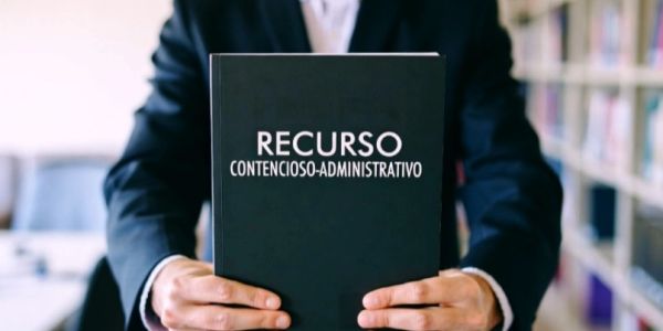 Persona sosteniendo un libro sobre recurso contencioso-administrativo.
