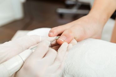 Close-up of a pedicure treatment shaping toenails with an electric file.