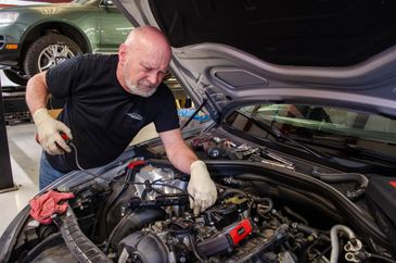 Mechanic working on a car engine with tools nearby.