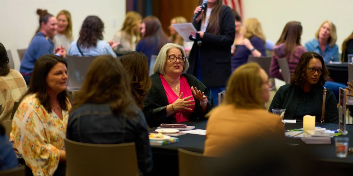 Women engaged in discussion at a conference table.