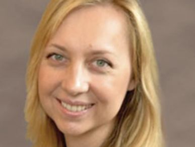 Smiling woman with blonde hair and green eyes.