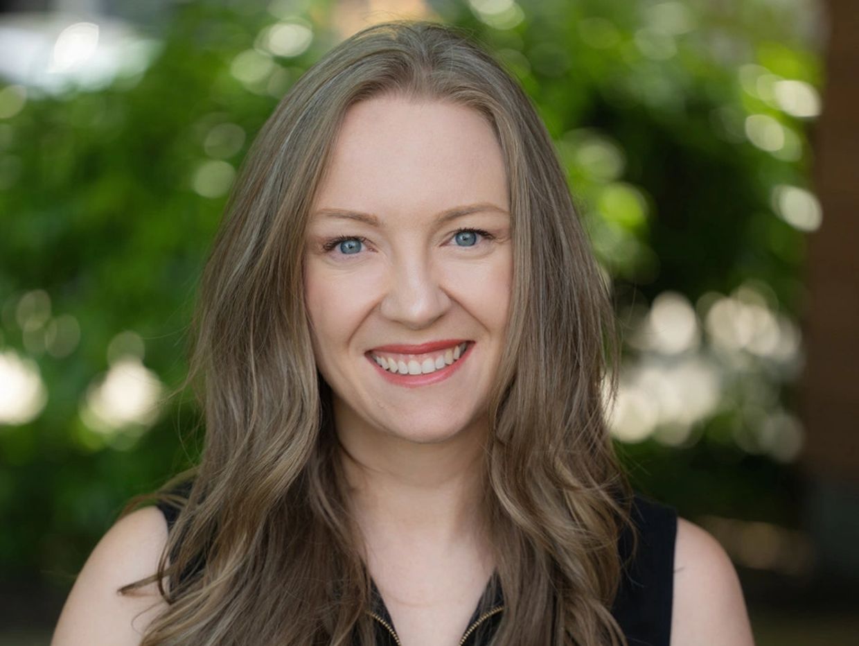 Smiling woman with long hair outdoors.