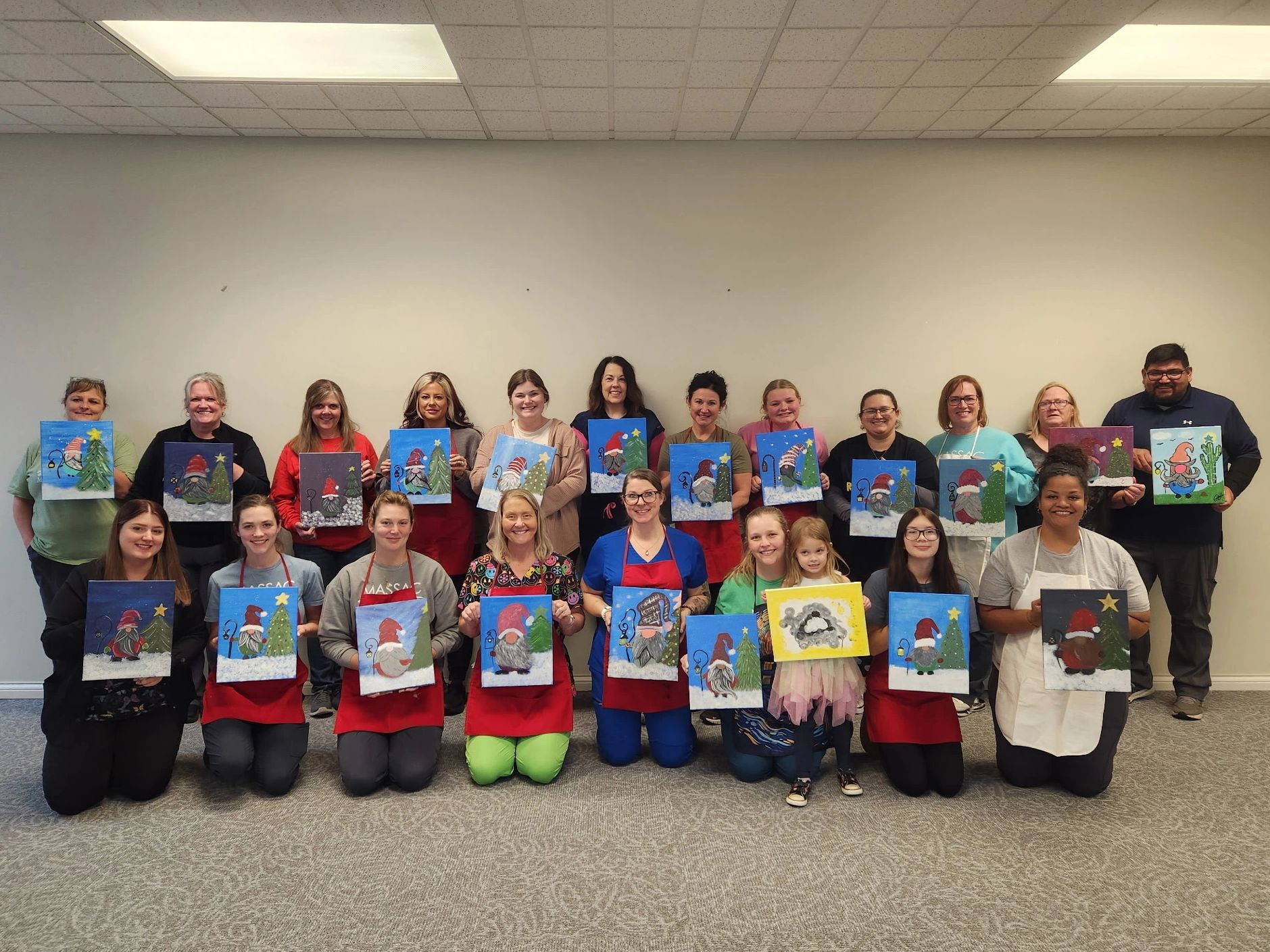Group of people proudly holding up their Christmas-themed paintings.