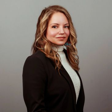 Professional woman with wavy hair in a black blazer.