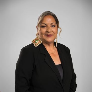 Confident woman in black blazer with statement earrings.