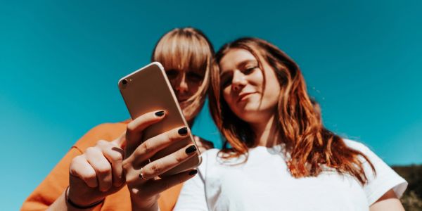 Two young women looking at a smartphone together.