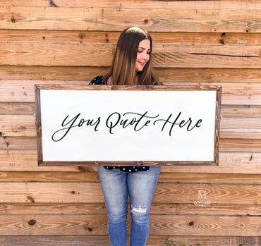 Woman holding a wooden-framed sign with elegant script saying 'Your Quote Here'.