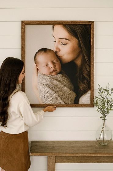 Woman admiring a large framed photo of a mother kissing her newborn baby.