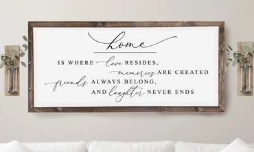 Framed wall art with a heartfelt home quote in elegant fonts above a white couch.