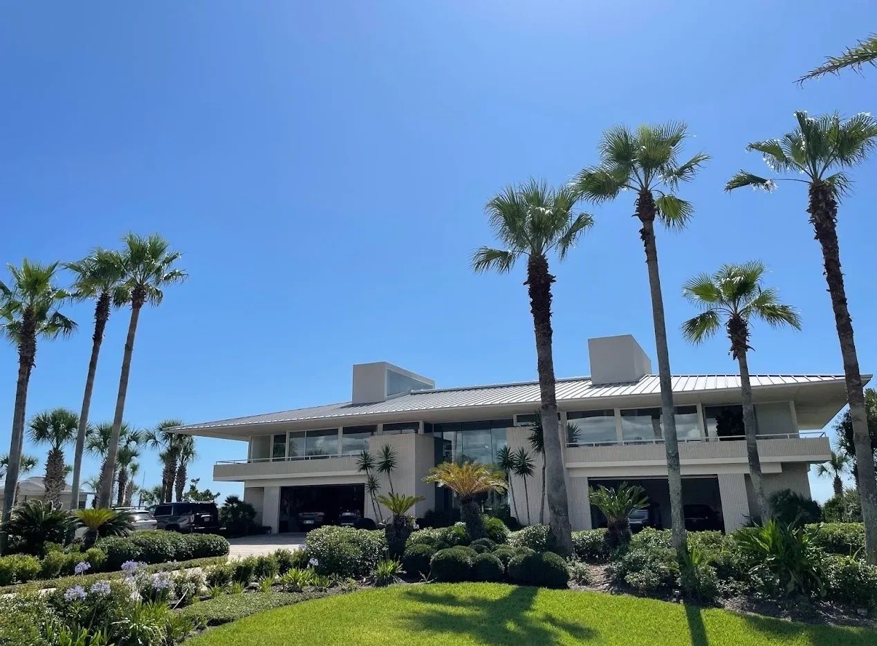 Modern house with palm trees and clear blue sky.