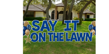 Large blue yard sign reads 'SAY IT ON THE LAWN' with balloons and a star.