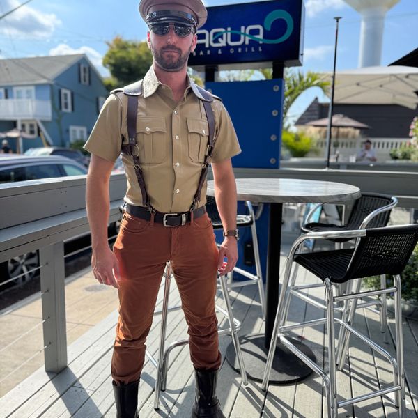 Man in vintage police uniform with sunglasses outdoors.