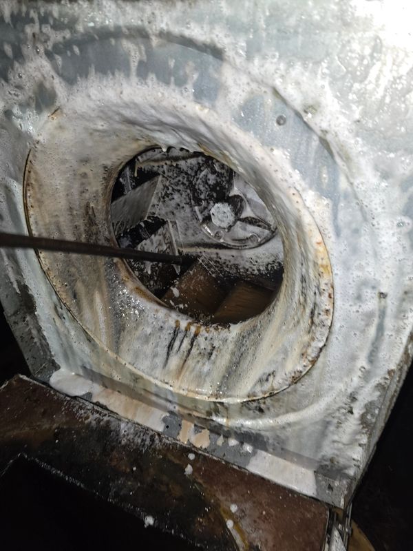 Dirty industrial fan covered in cleaning foam.