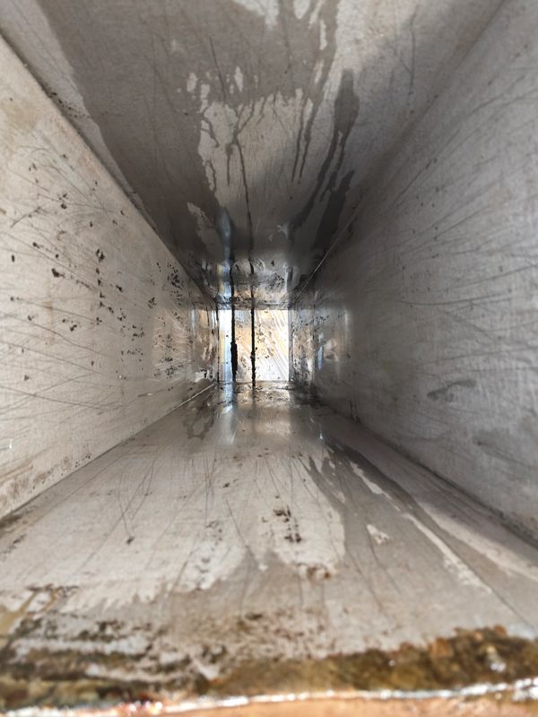 Inside view of a dirty, rusty metal duct or vent.