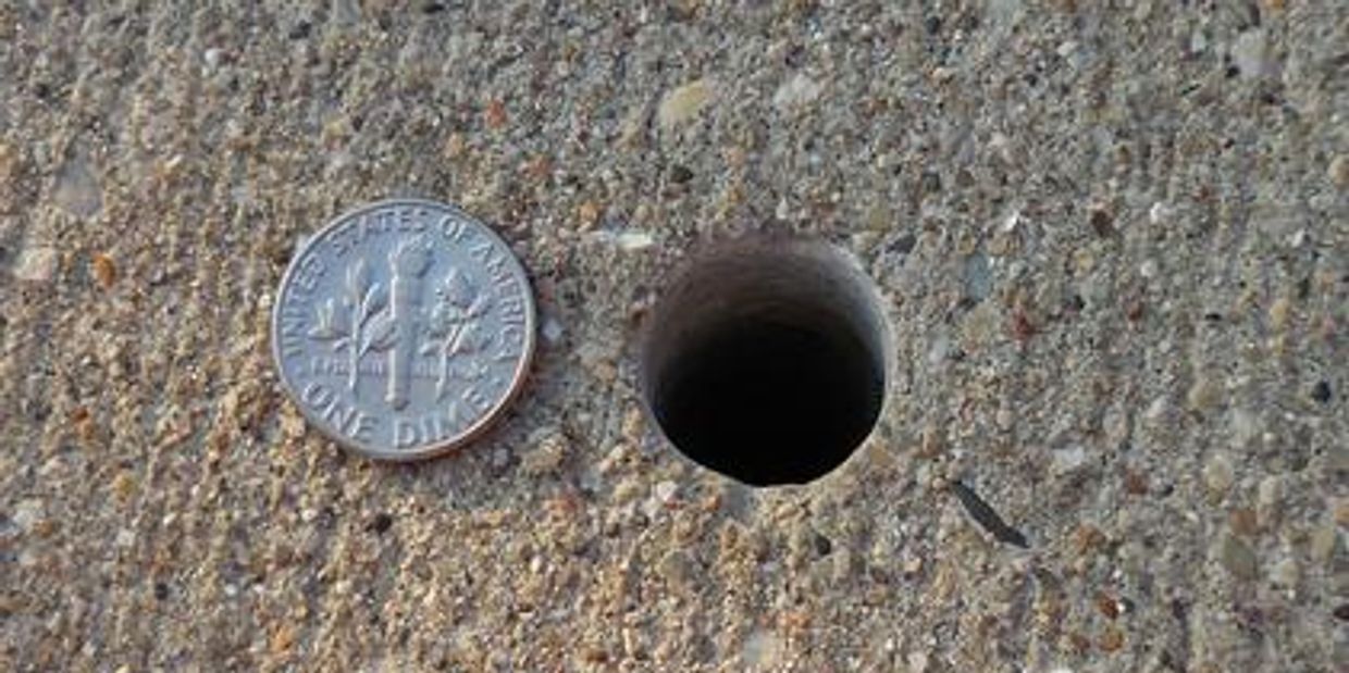 Drilled hole closeup with dime showing small size needed for injection ports