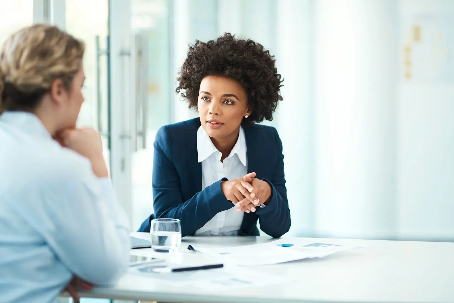 Two professional women engaged in a serious business conversation in an office.