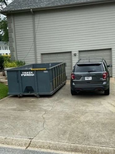 15 yard dumpster in driveway beside car