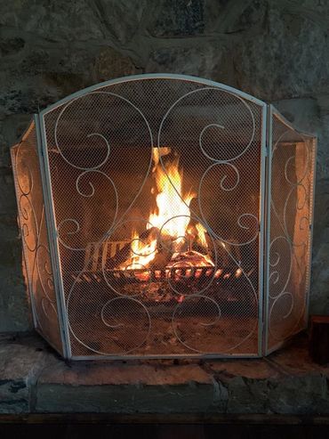 Cozy fireplace with a decorative metal screen and glowing fire.
