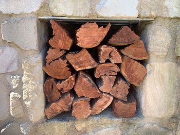 Stacked firewood in a stone wall niche.