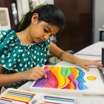 Young girl coloring a vibrant abstract drawing with colored pencils.