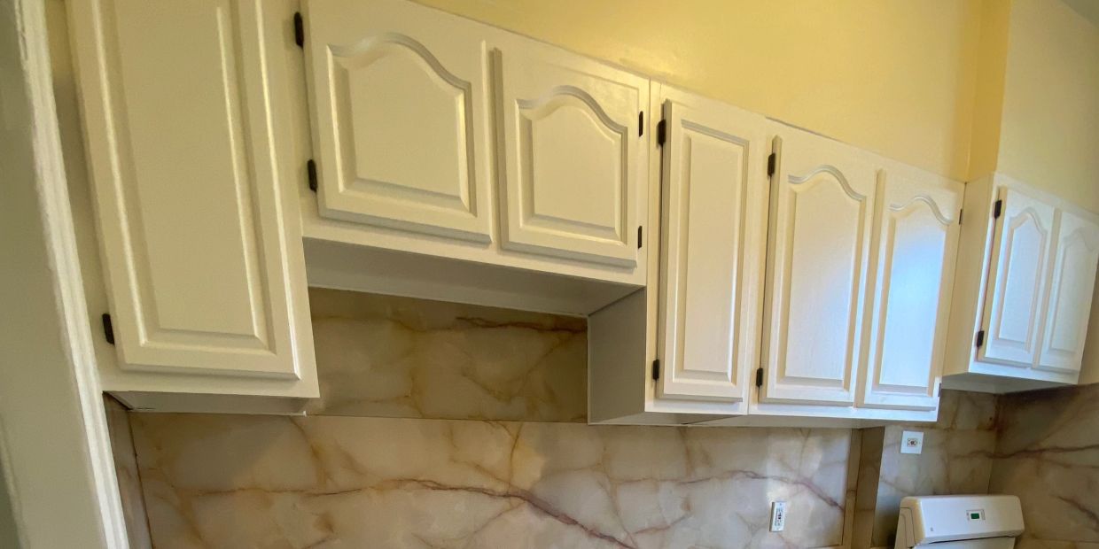 White kitchen cabinets with a marble backsplash.