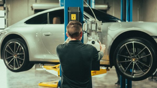 Auto technician lifting Porsche 911 on Rotary lift at Wolfpen Euro Auto Repair in Roswell, GA