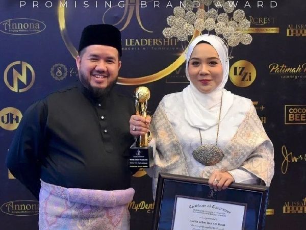 Award event backdrop with two people holding a trophy and certificate for Jamu Tun Teja Sdn Bhd.