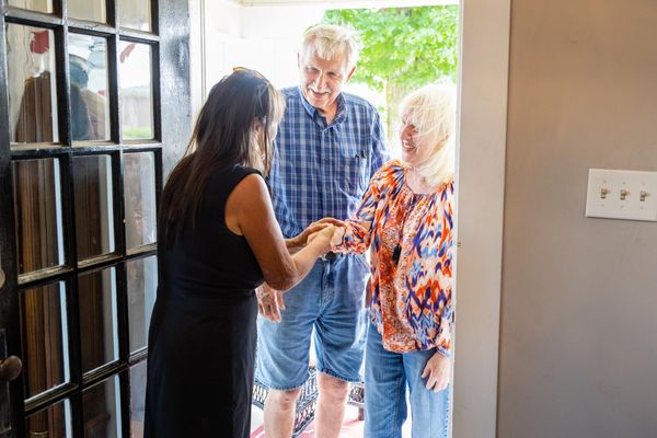 A lady meeting hand with some old persons in a room