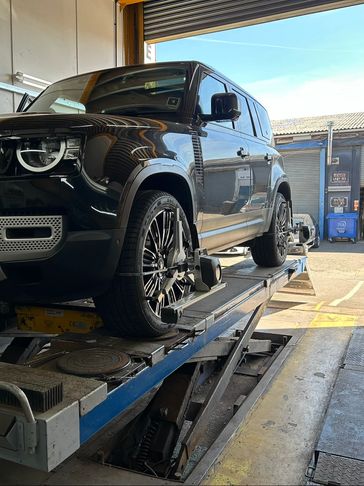 Black Land Rover Defender on a car lift inside a garage.